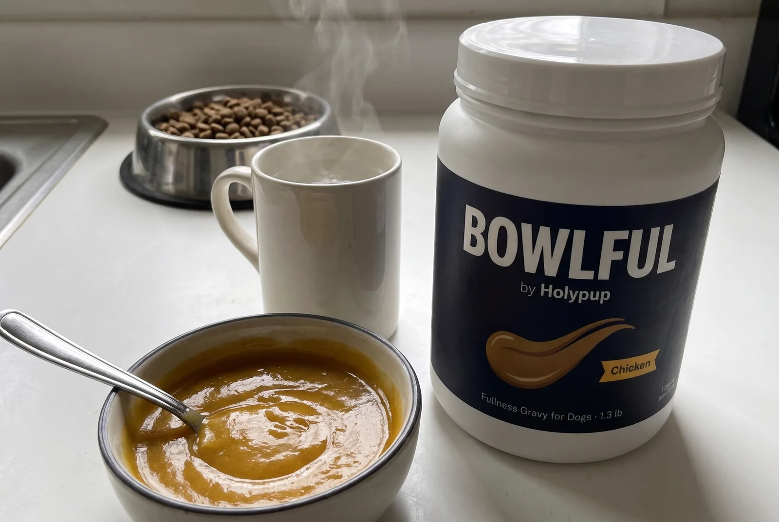 The BOWLFUL can on a kitchen counter next to a mug of warm water and a bowl of prepared gravy
